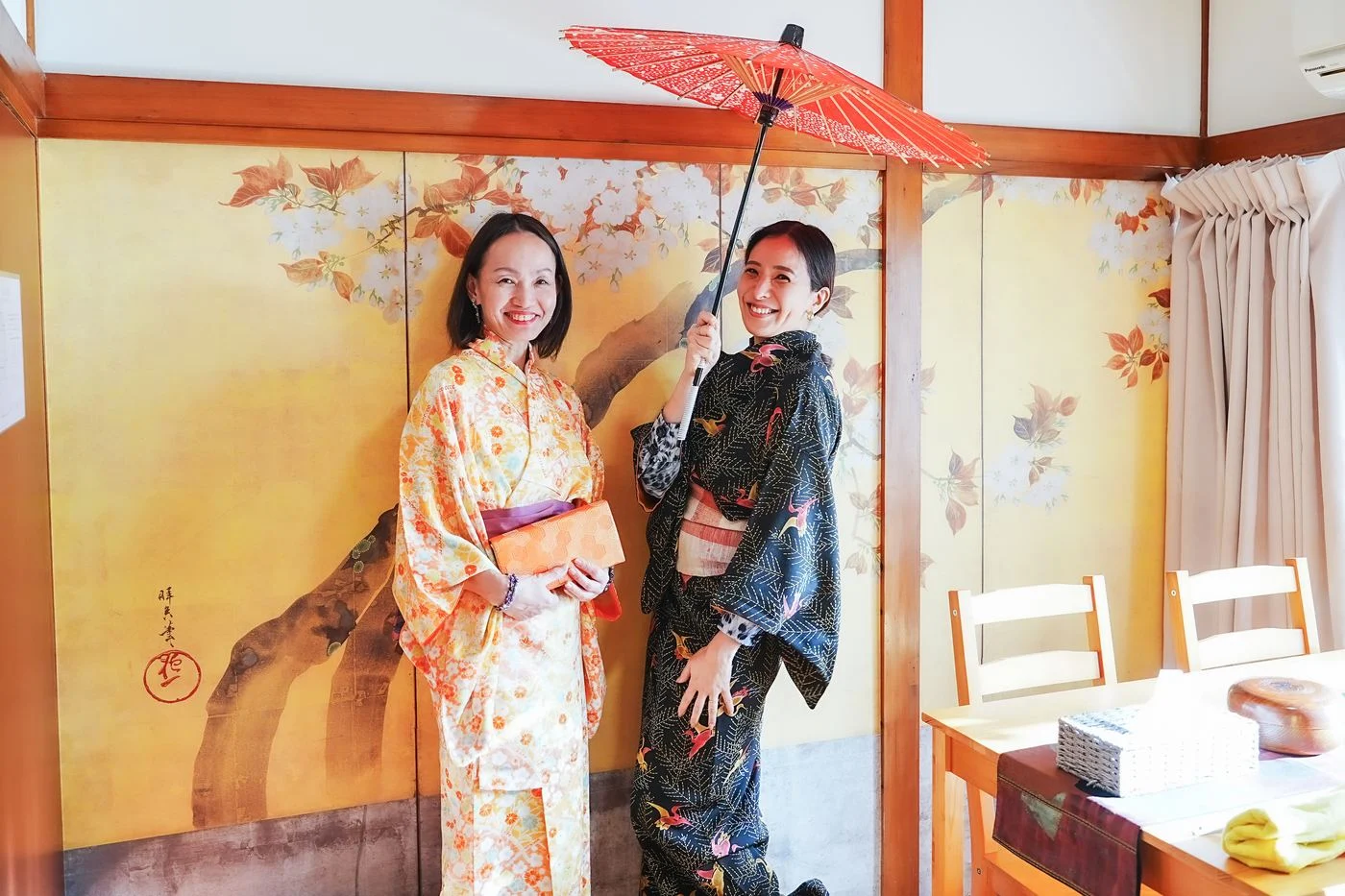 Two guests in kimono under a red umbrella